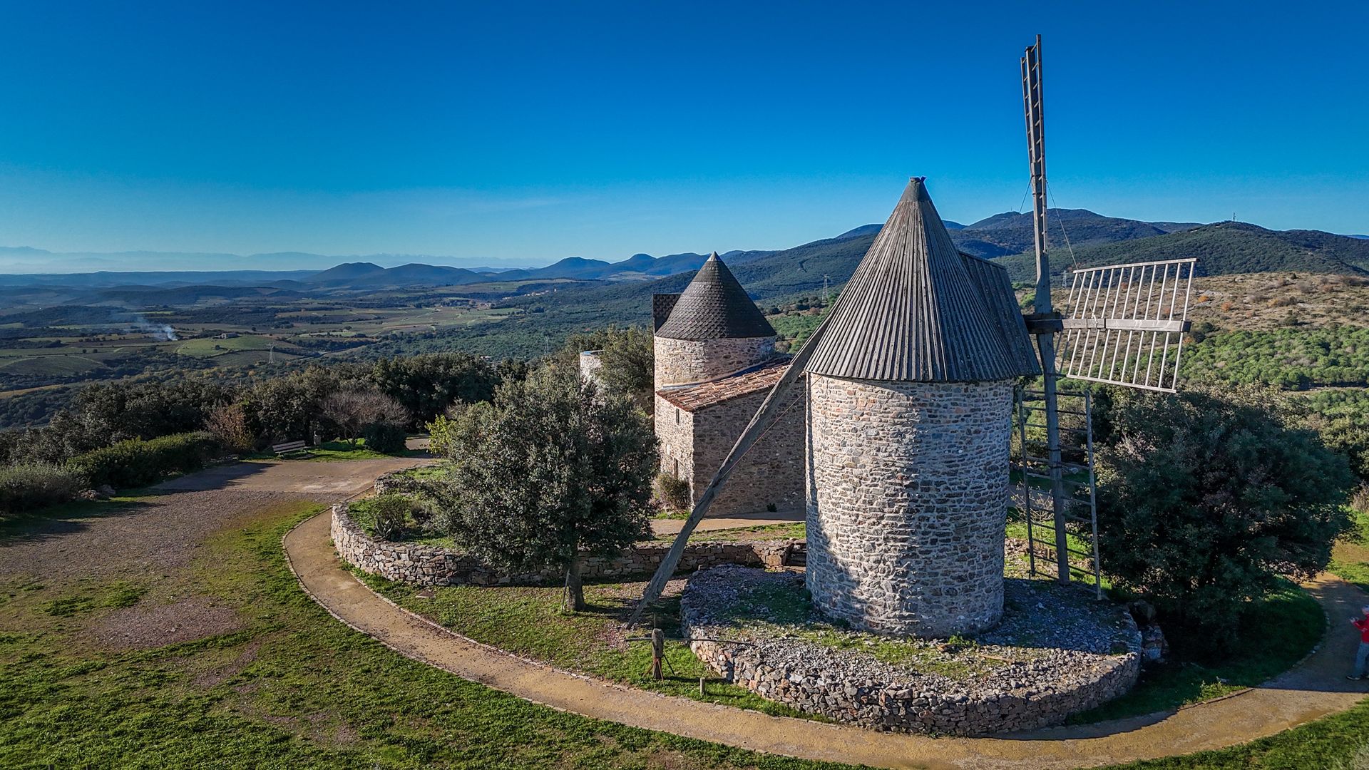Vue sur les moulins de Faugères dans les avant-monts et son panorama sur la plaine viticole