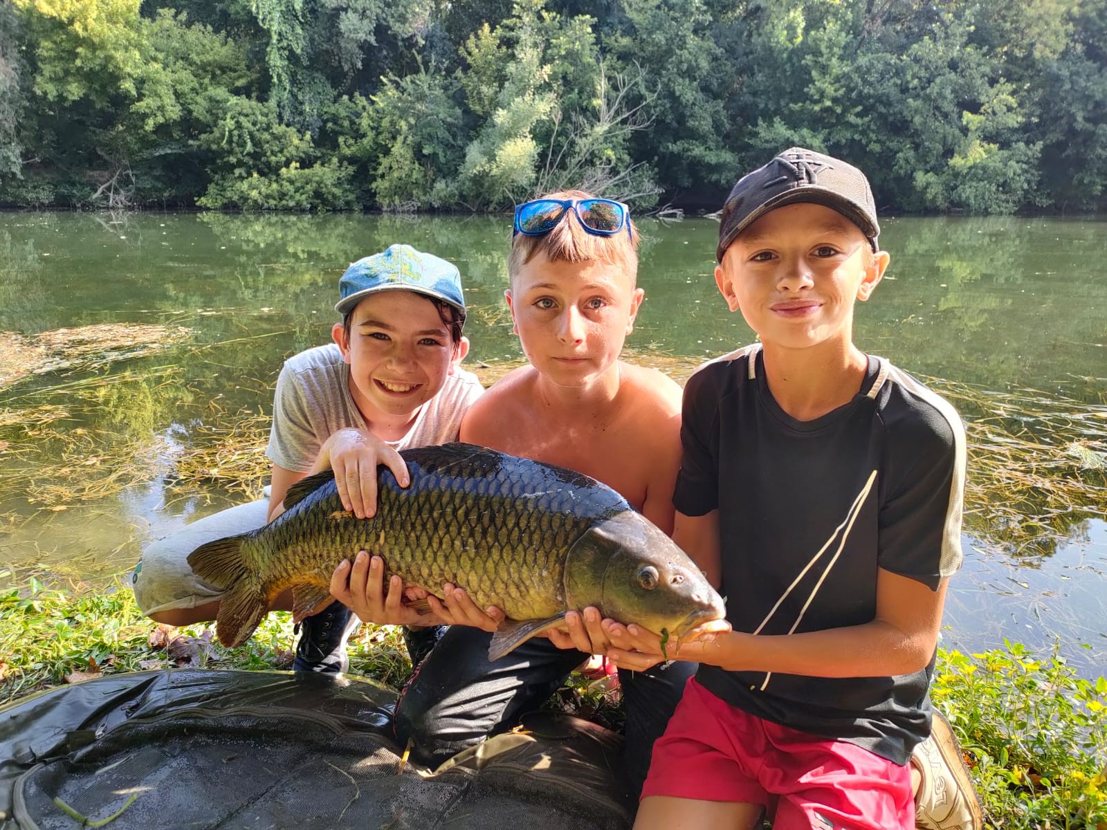 Trois jeunes garçons viennent de pêcher un poisson dans le fleuve Hérault