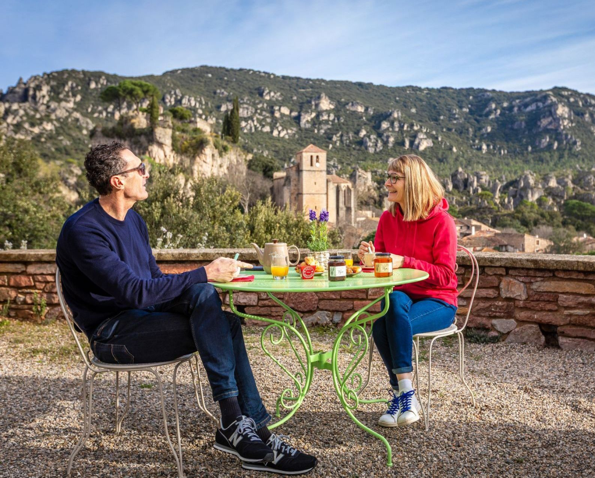 Couple qui prend son petit-déjeuner sur la terrasse extérieur de l'hôtel Les Hauts de Mourèze
