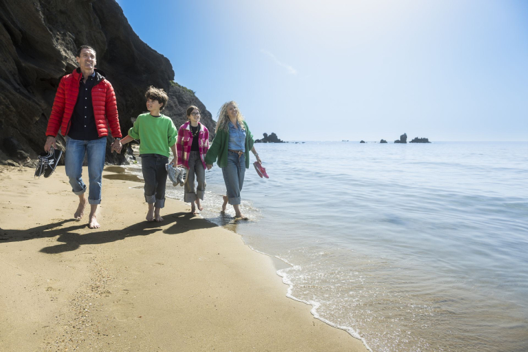 Une famille se promène les pieds dans l'eau sur la plage de la plagette au Cap d'Agde